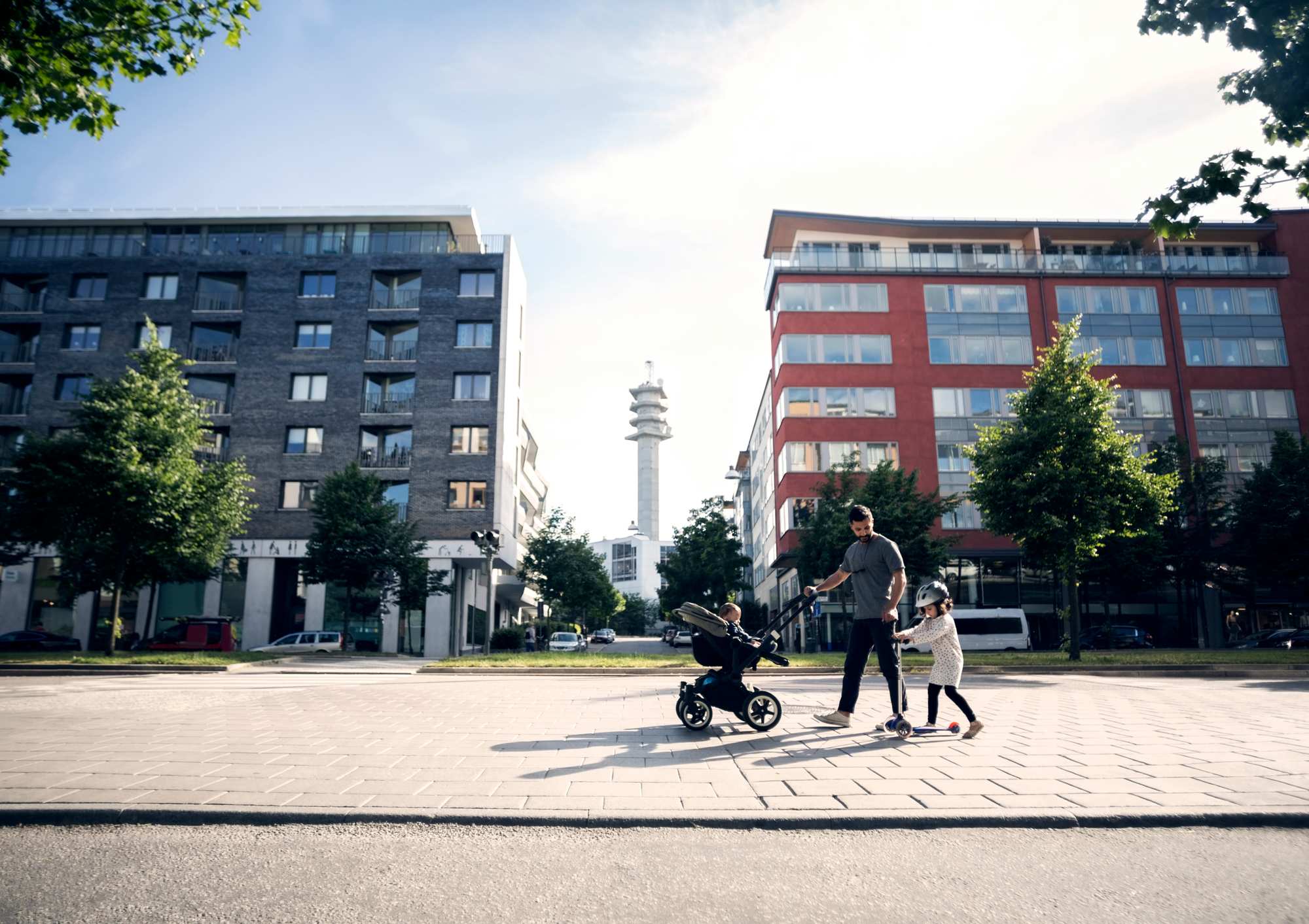 En man går med ett barn framför hus